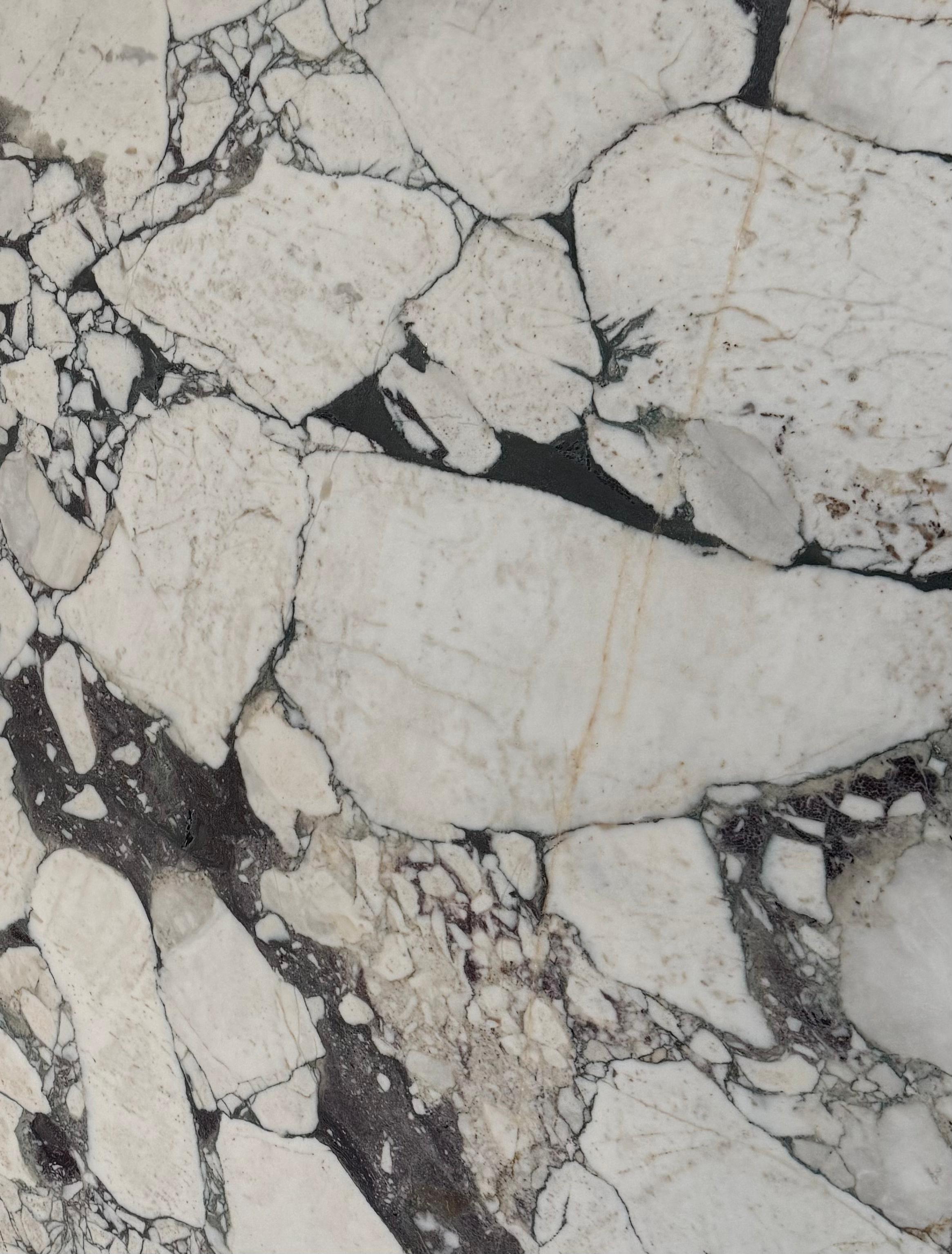 Close-up of Calacatta Viola Marble sample with deep burgundy veining and soft white base – natural stone texture for interior design.