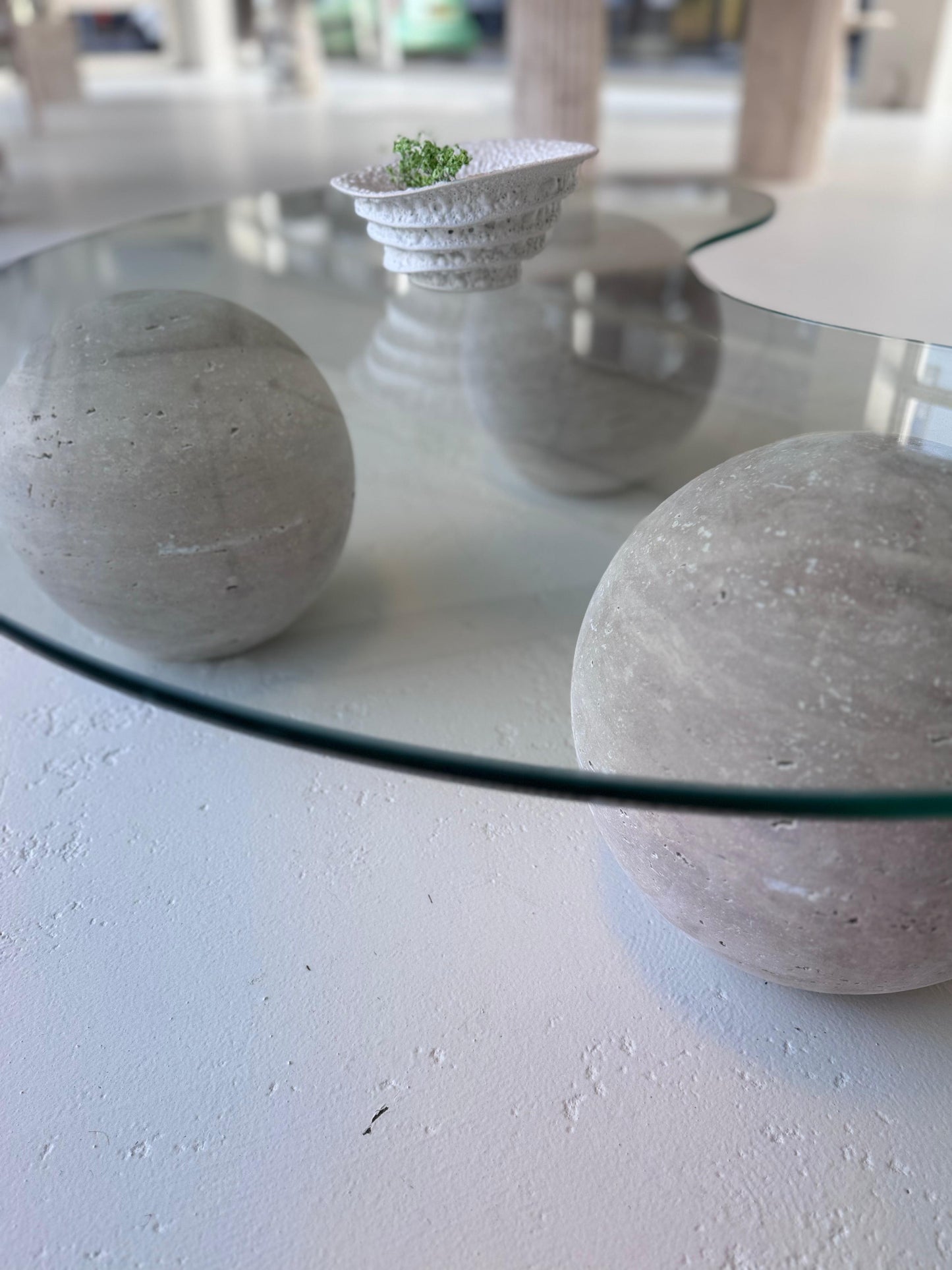 World Globe Organic-shaped Coffee Table with glass top and sculptural travertine base in a modern interior