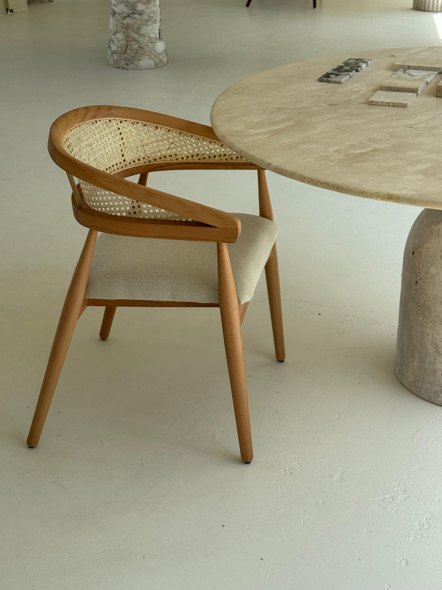Gaia Dining Chair with walnut-stained frame and woven cane backrest in light brown setting