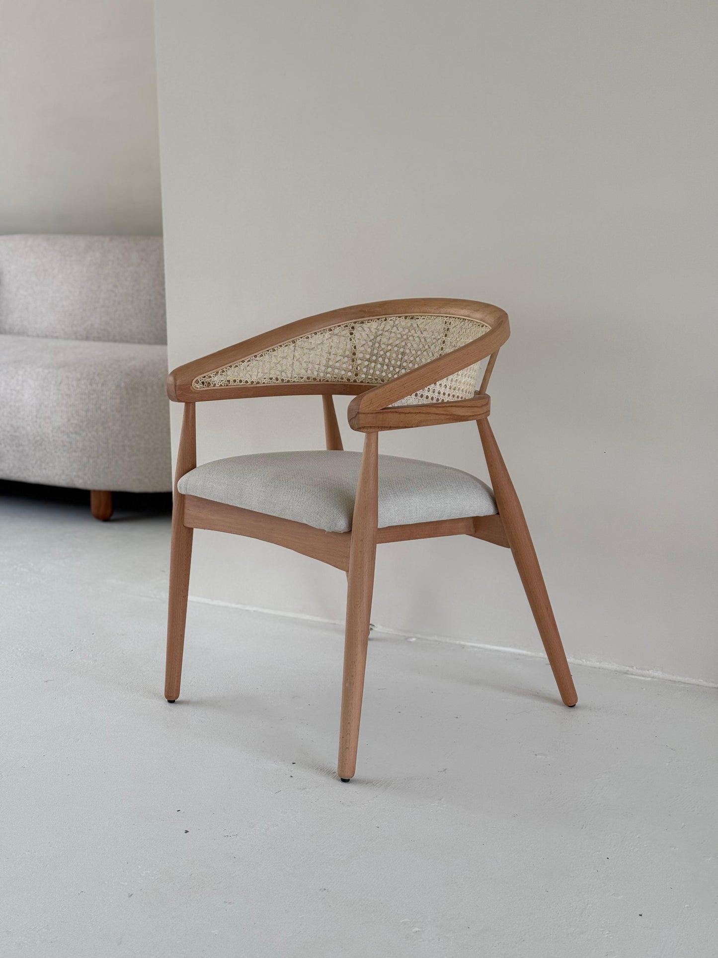 Side view of Gaia Dining Chair showing curved armrests and elegant wood grain