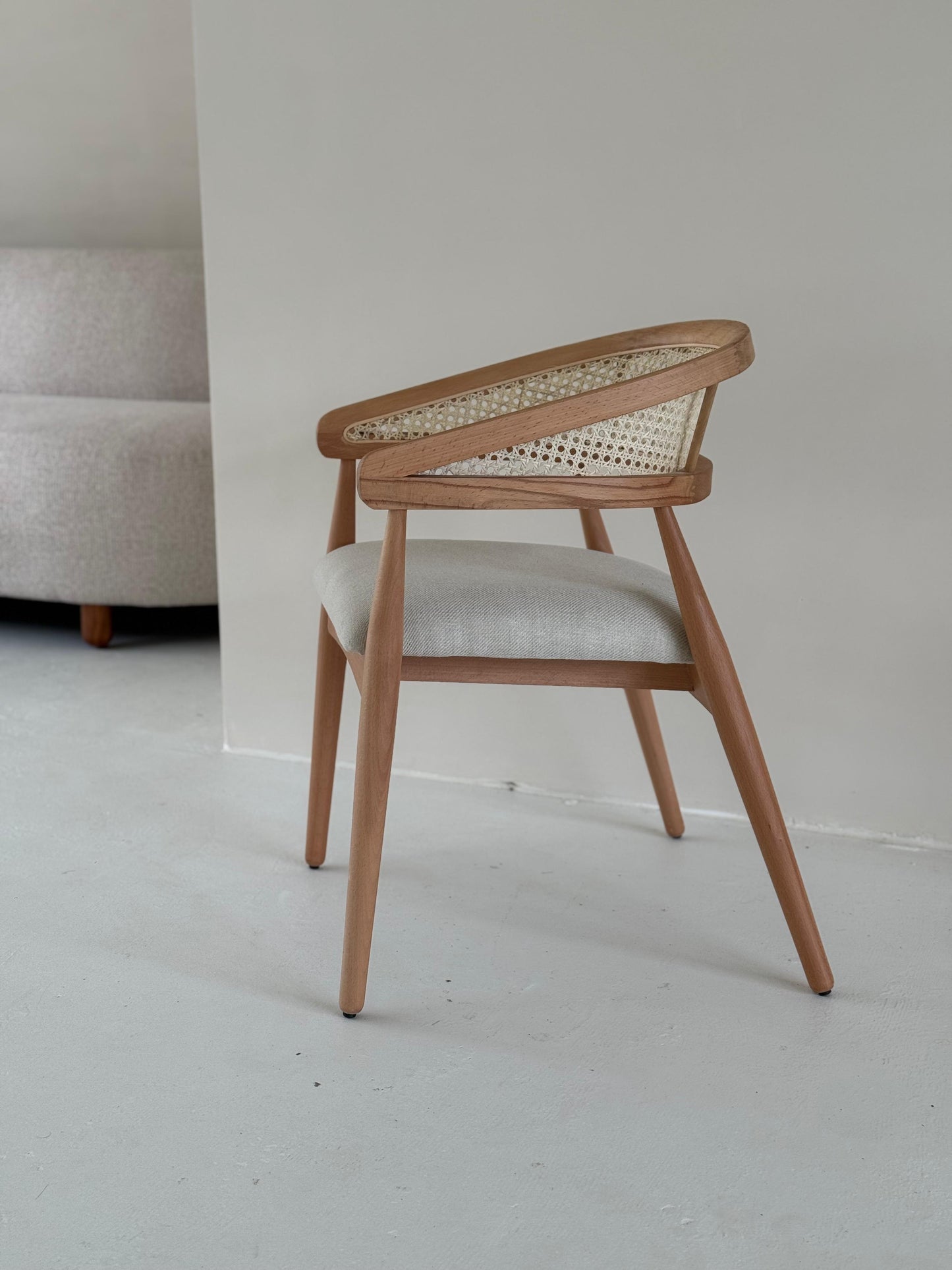 Side view of Gaia Dining Chair showing curved armrests and elegant wood grain
