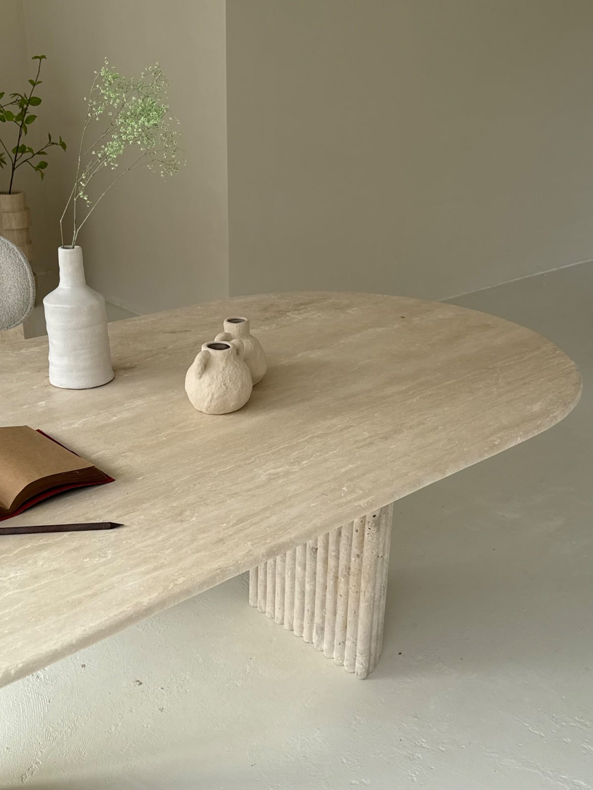 Travertine oval dining table Bambusa with vein cut top and spider base in daylight interior