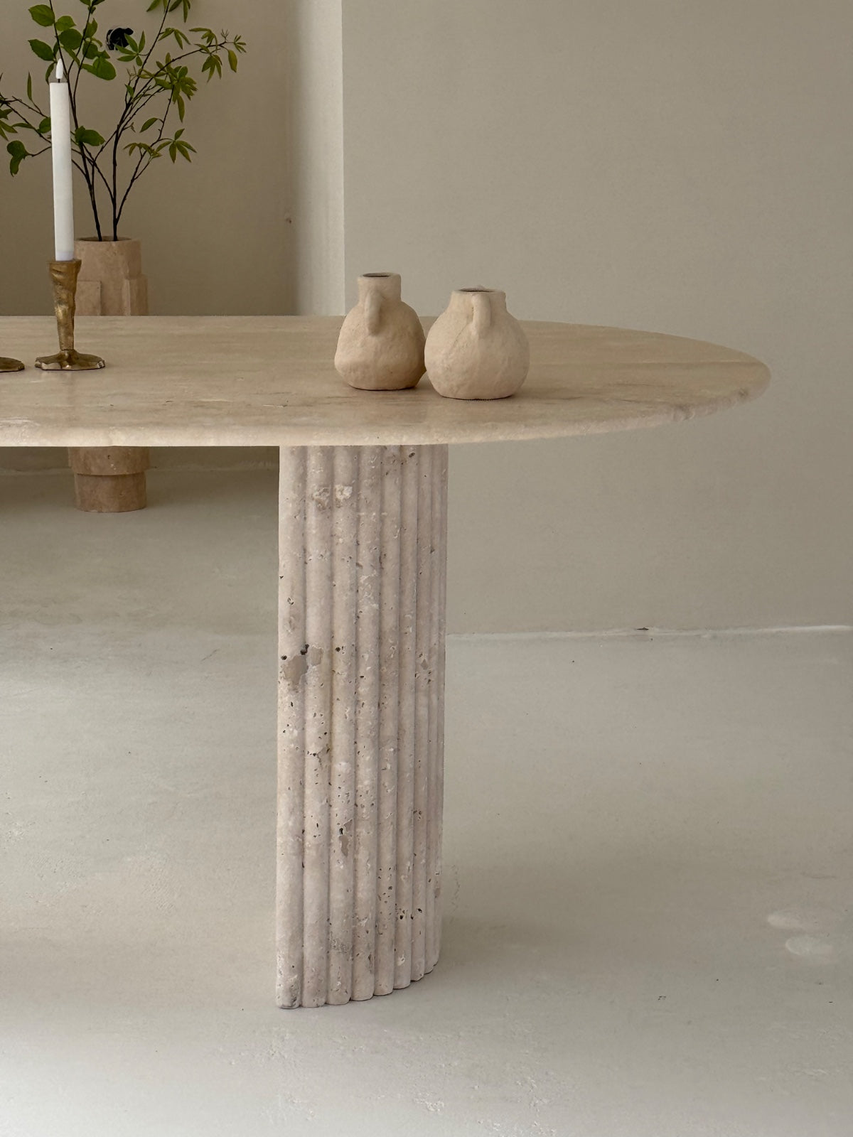 Travertine oval dining table Bambusa with vein cut top and spider base in daylight interior