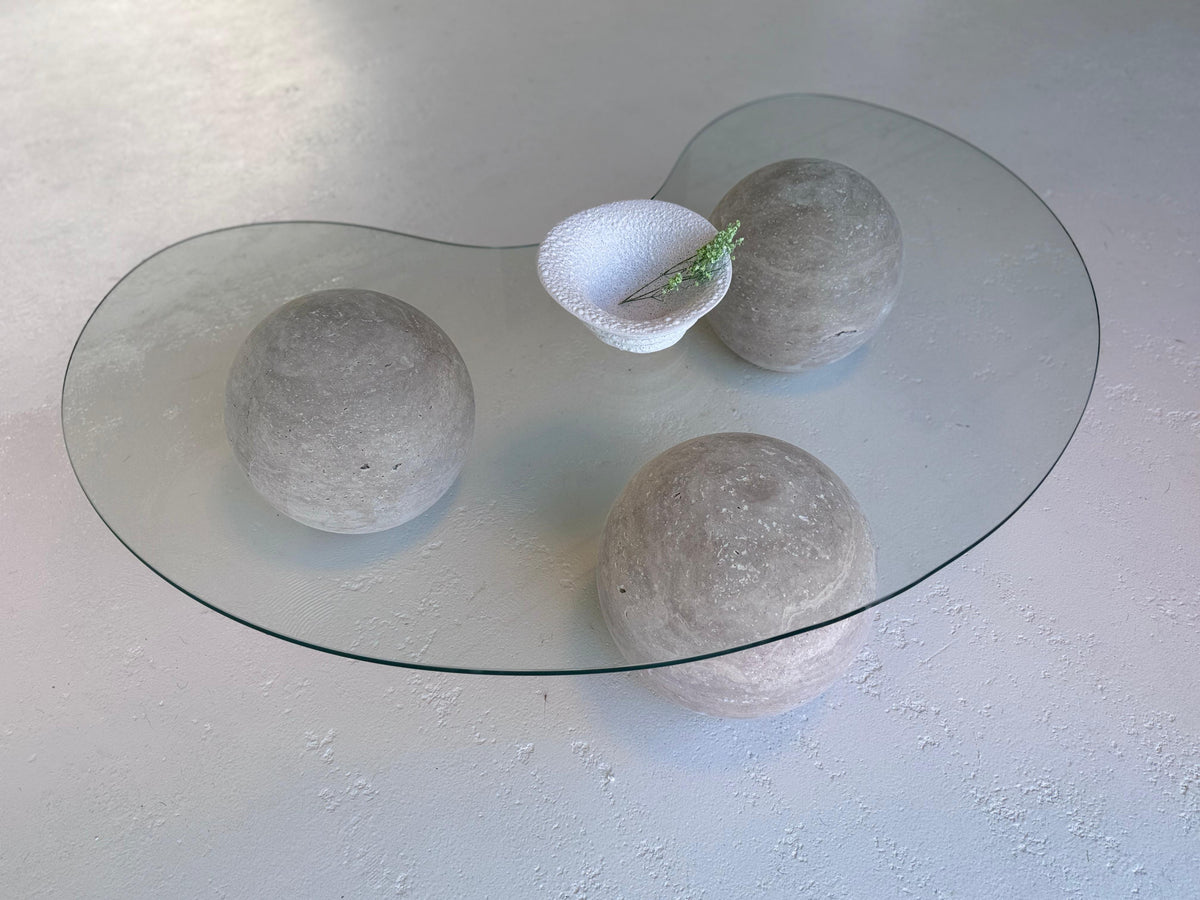 World Globe Organic-shaped Coffee Table with glass top and sculptural travertine base in a modern interior