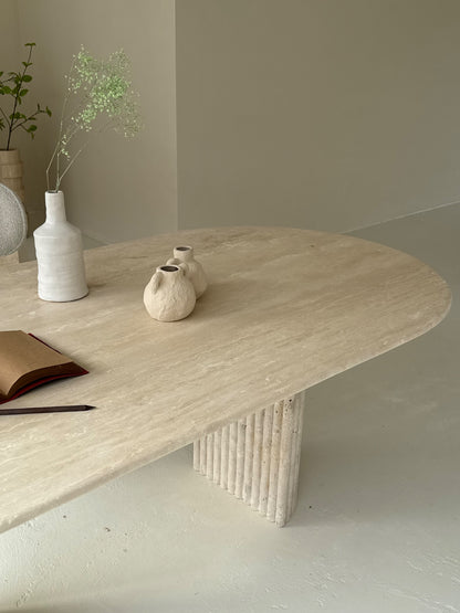 Travertine oval dining table Bambusa with vein cut top and spider base in daylight interior