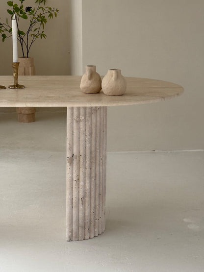 Travertine oval dining table Bambusa with vein cut top and spider base in daylight interior