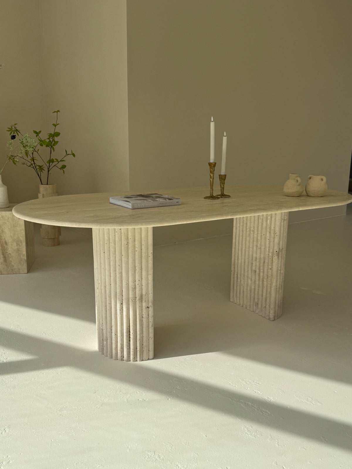 Travertine oval dining table Bambusa with vein cut top and spider base in daylight interior