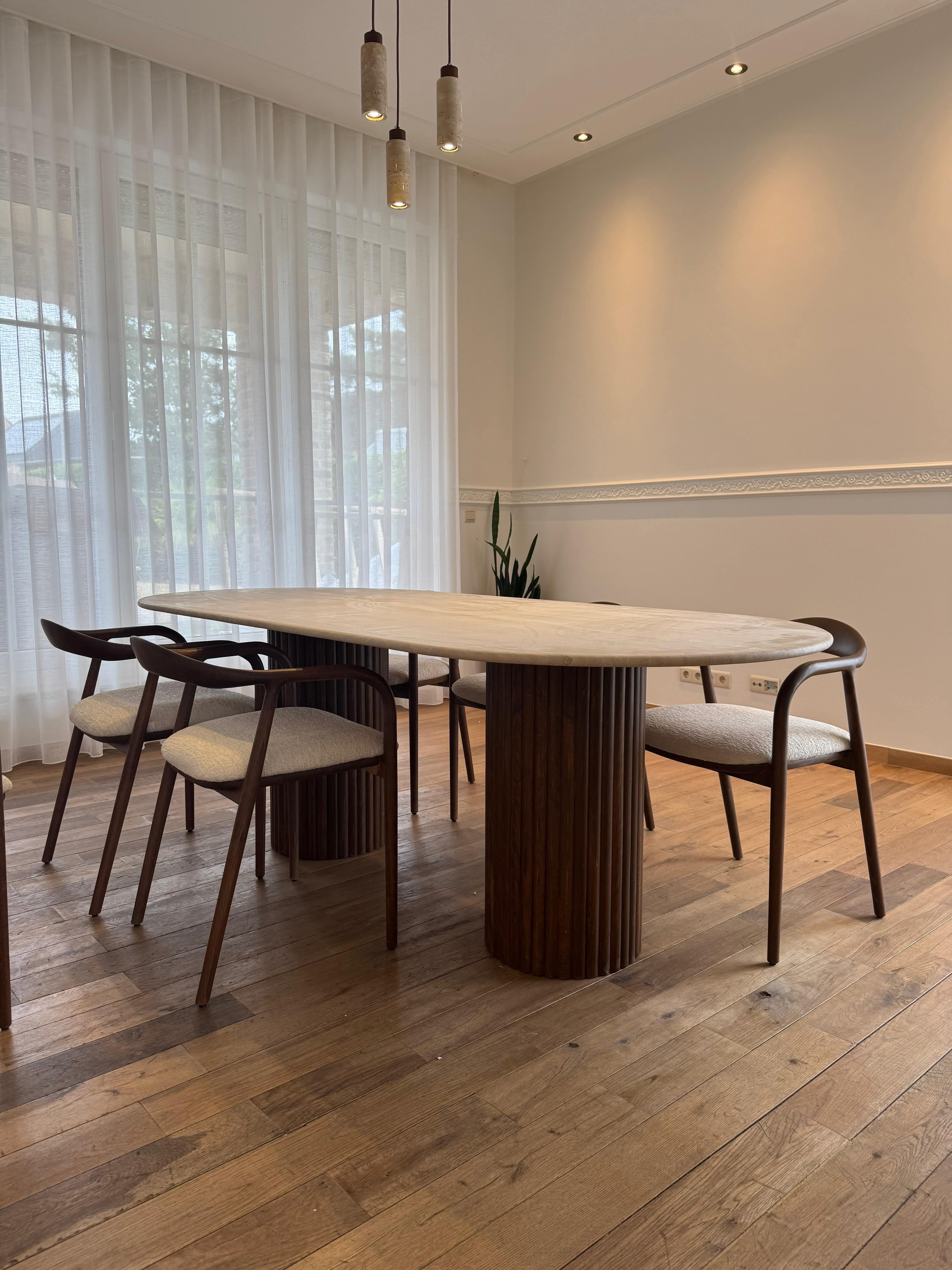 Close-up of the ribbed wooden legs and natural stone texture of the oval dining table, highlighting craftsmanship and material detail.