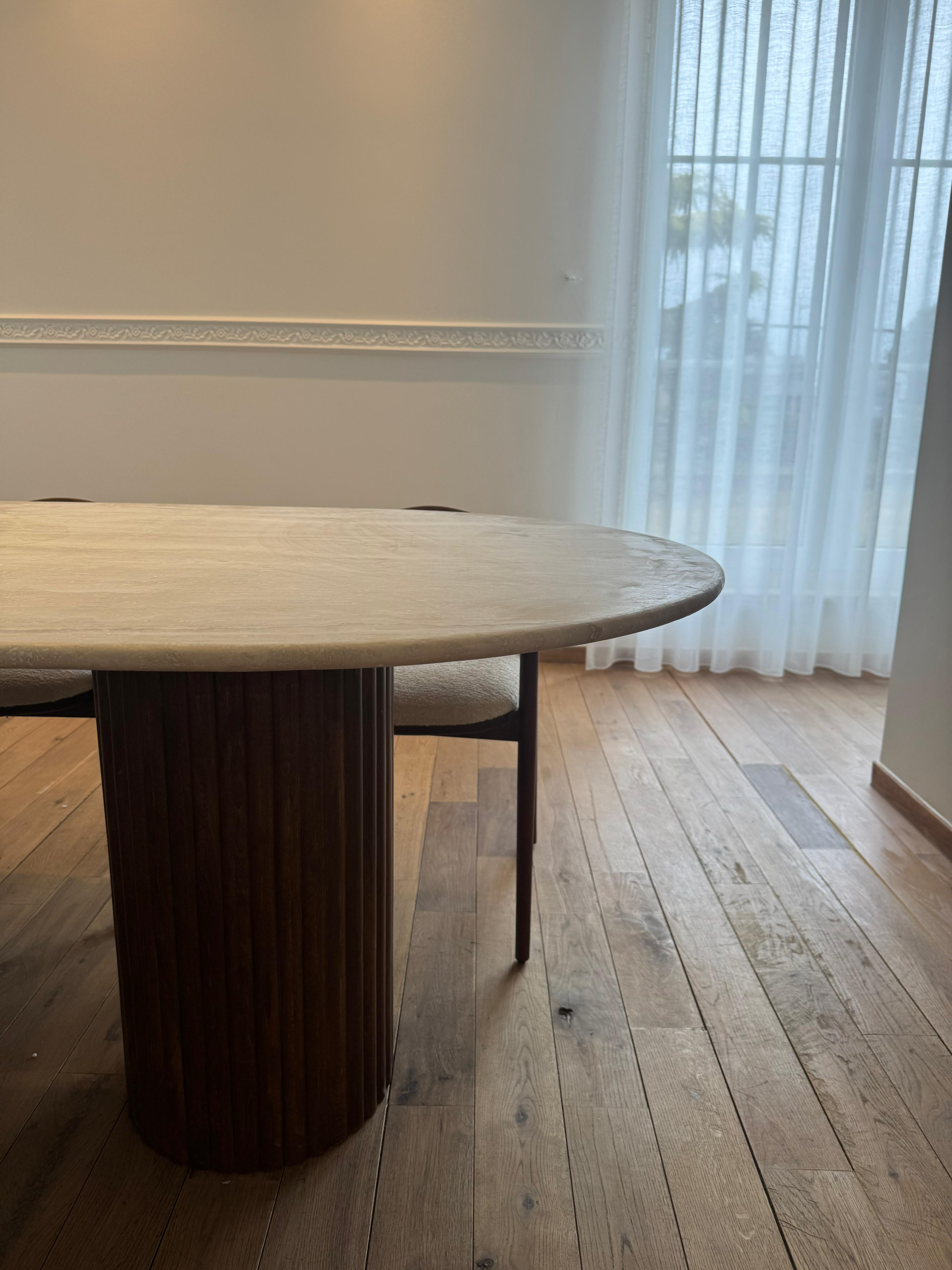 Close-up of the ribbed wooden legs and natural stone texture of the oval dining table, highlighting craftsmanship and material detail.