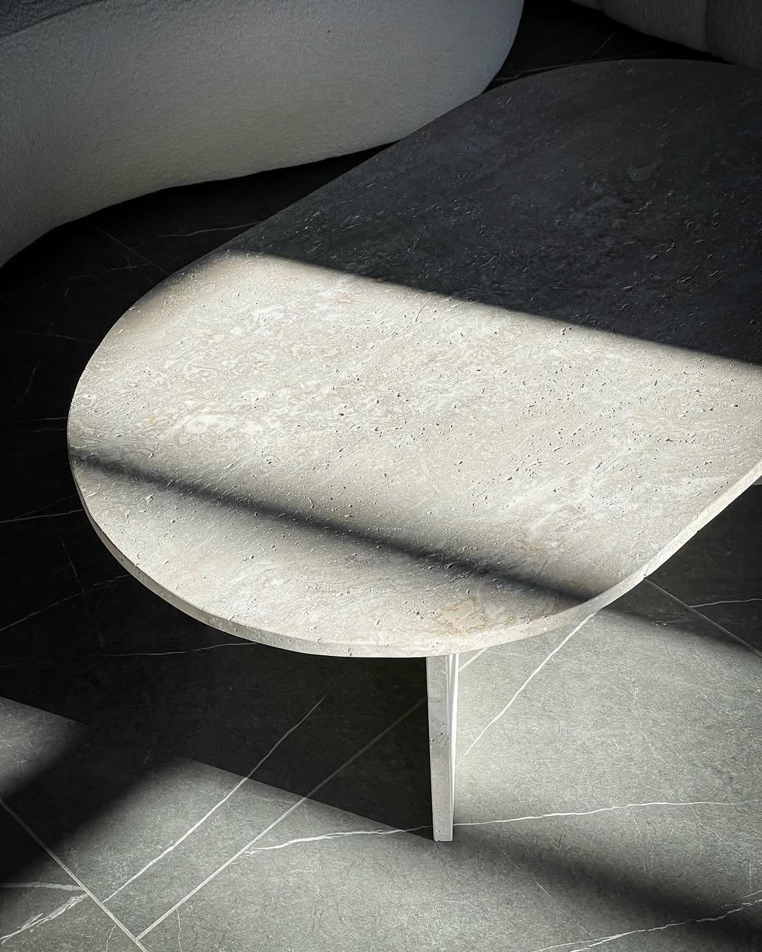 Twin Fold Travertine Coffee Table with twin-panel base and crosscut stone surface in a modern living room