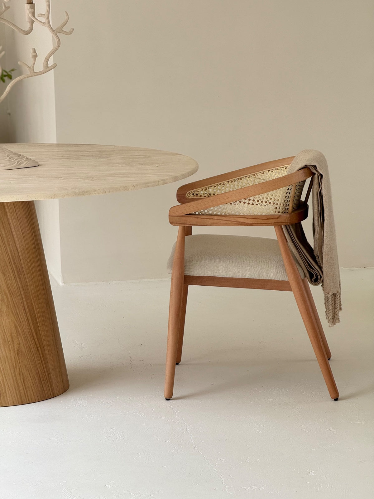 Gaia Dining Chair with walnut-stained frame and woven cane backrest in light brown setting